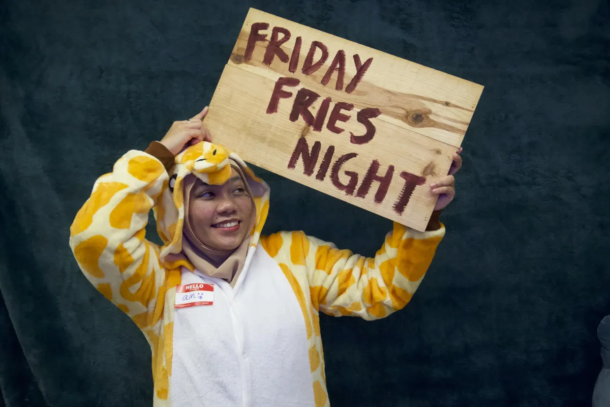 A participant holds a hand-painted Friday Fries Night sign.